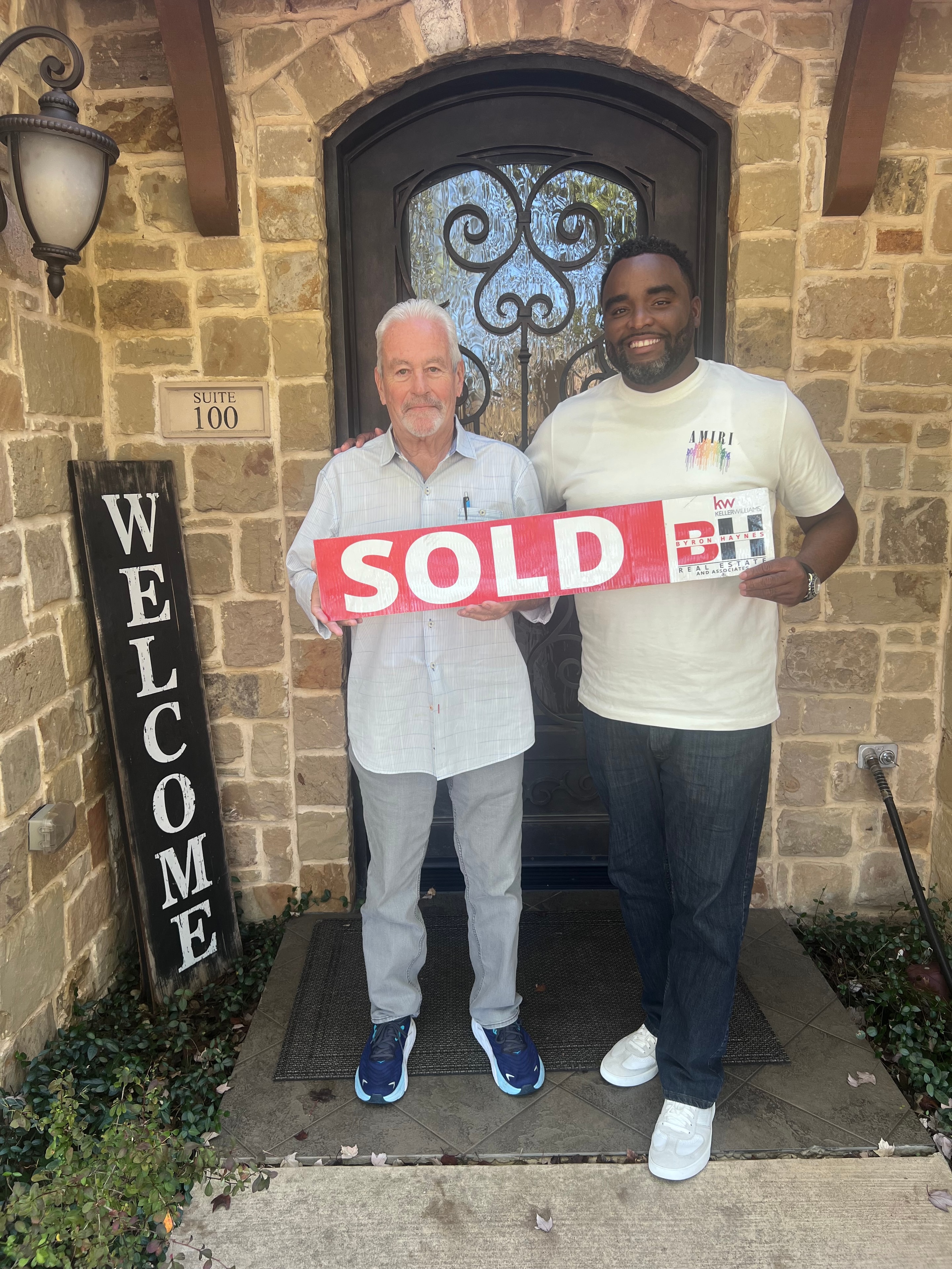 Byron Haynes with happy clients holding a Sold sign at their new home